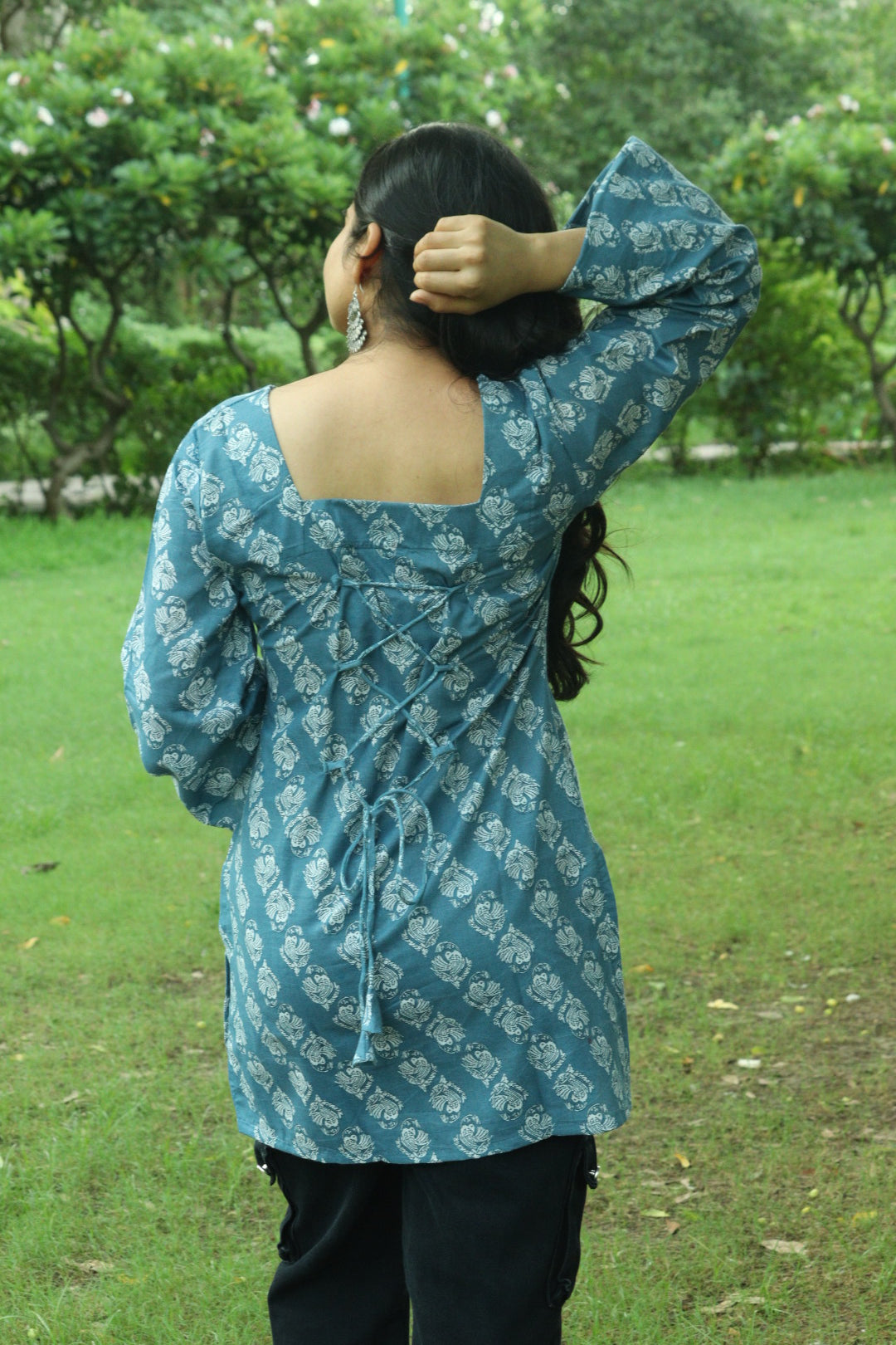 Close-up of a teal blue short kurti with ivory block-printed motifs, square neckline and flared bell sleeves.